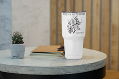 a white cup sitting on top of a table next to a plant