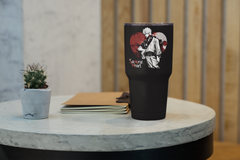 a black cup sitting on top of a table next to a plant