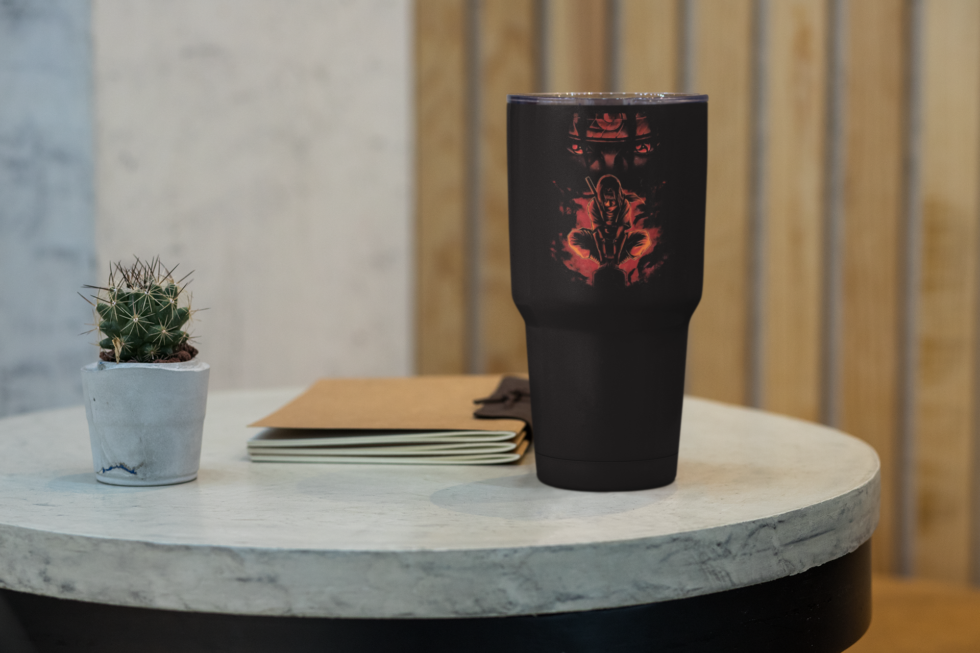 a black cup sitting on top of a table next to a plant
