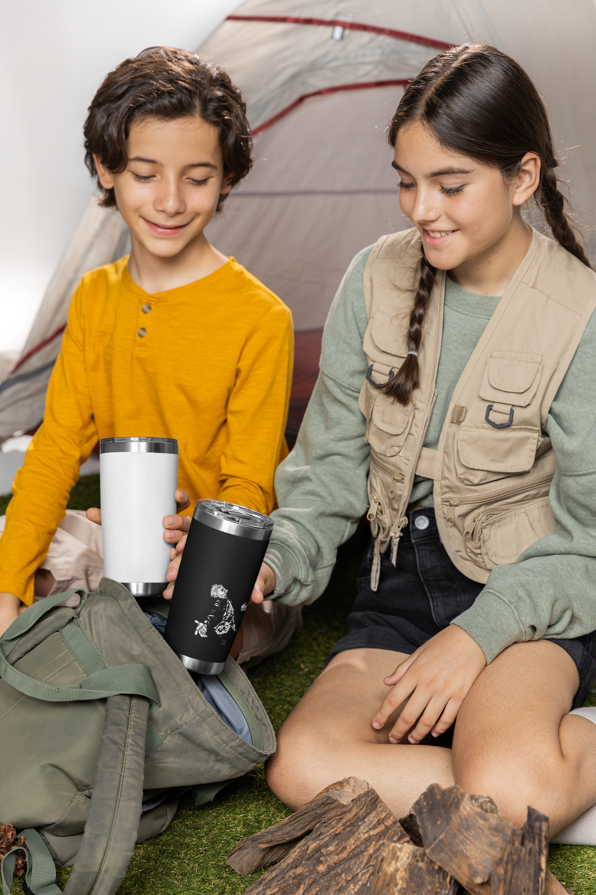 two young girls sitting on the ground next to a tent