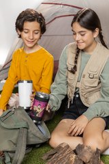 two young girls sitting on the ground next to a tent