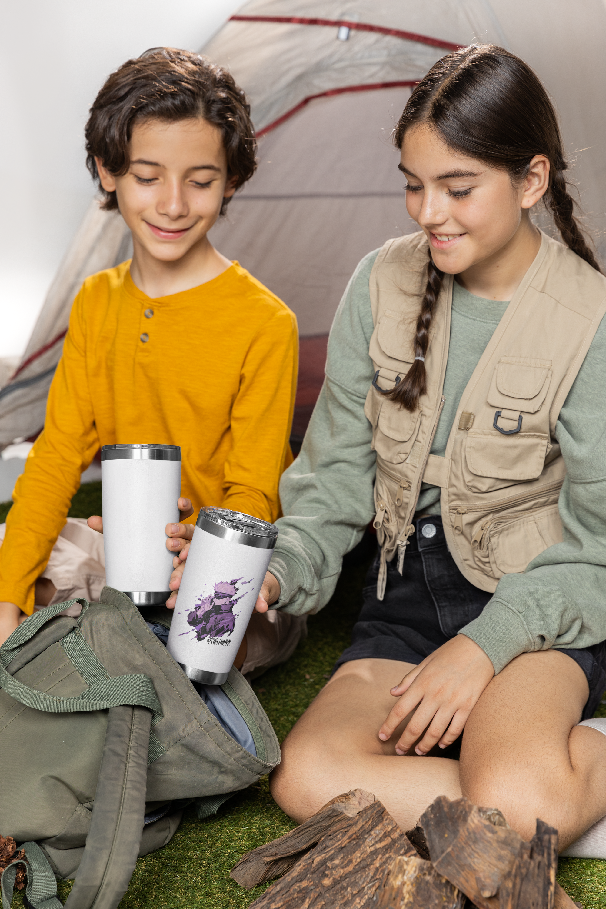 two young girls sitting on the ground next to a tent