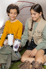 two young girls sitting on the ground next to a tent