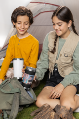 two young girls sitting on the ground next to a tent