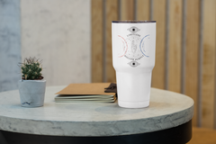 a white cup sitting on top of a table next to a plant