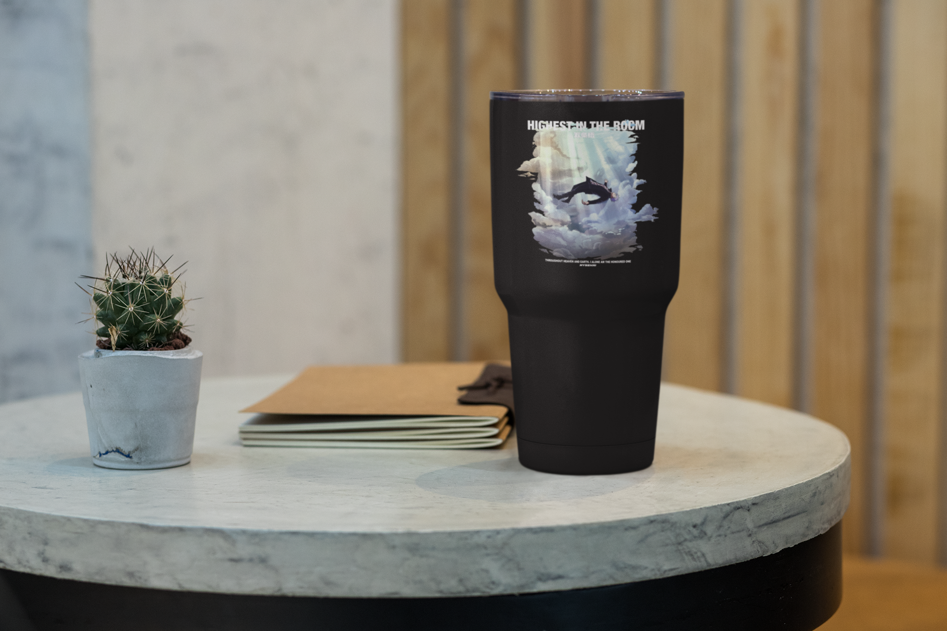 a black cup sitting on top of a table next to a plant