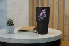 a black cup sitting on top of a table next to a plant