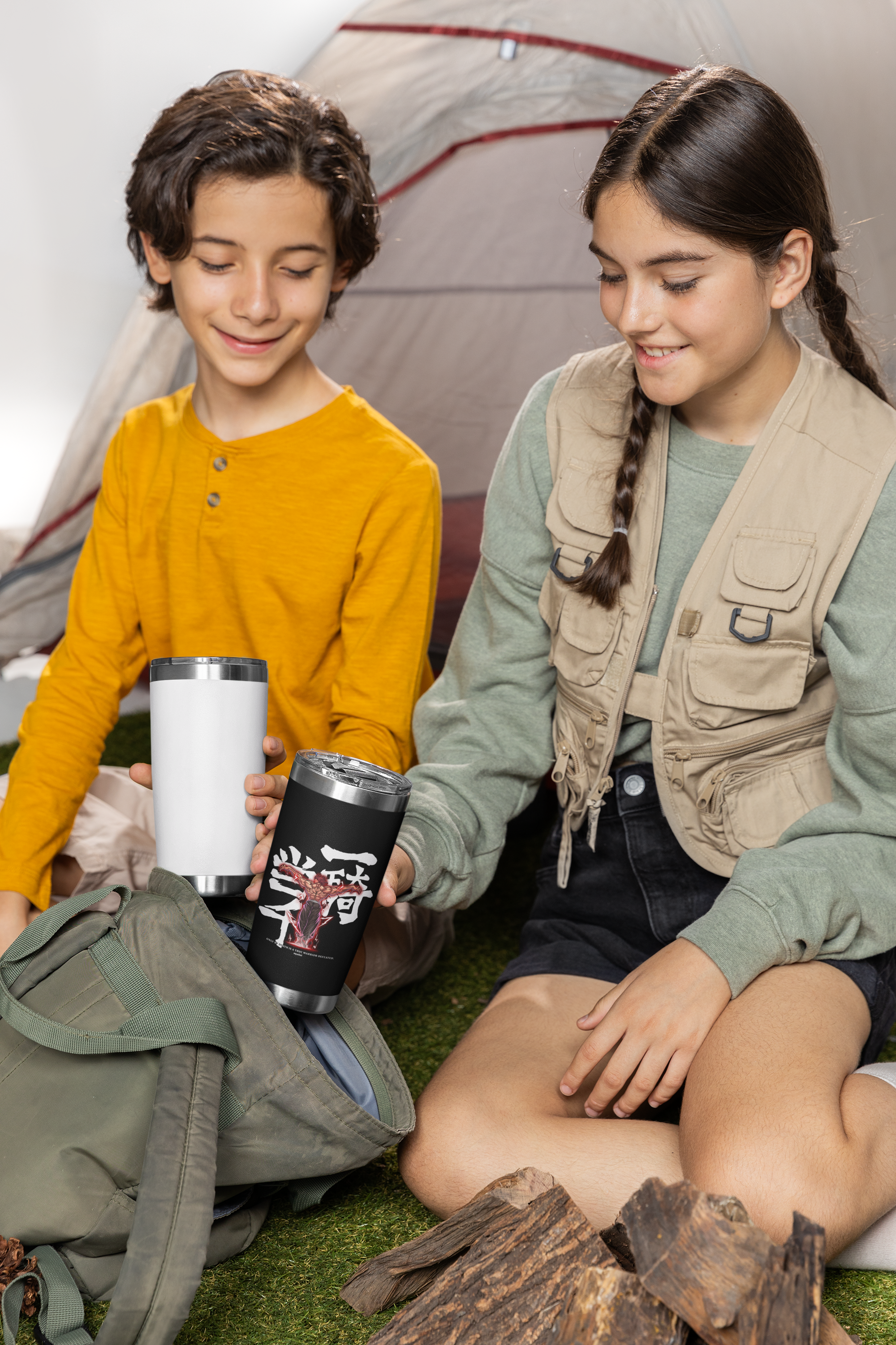 two young girls sitting on the ground next to a tent