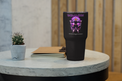 a black cup sitting on top of a table next to a plant