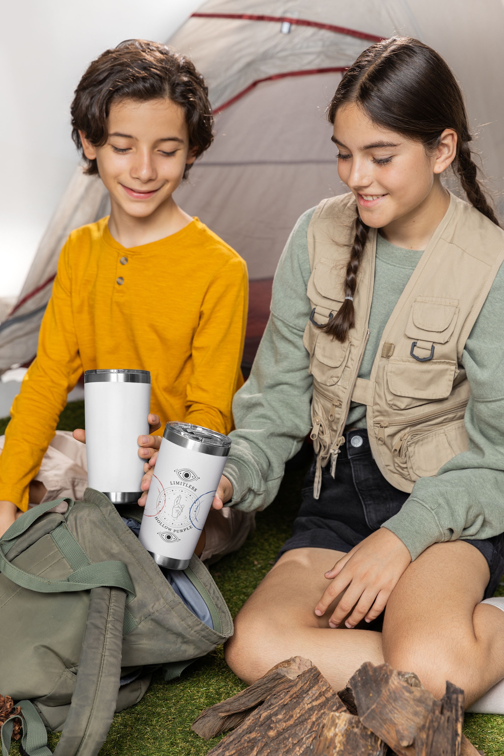 two young girls sitting on the ground next to a tent